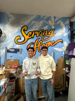 Two youth volunteers against Serving Hope backdrop poster